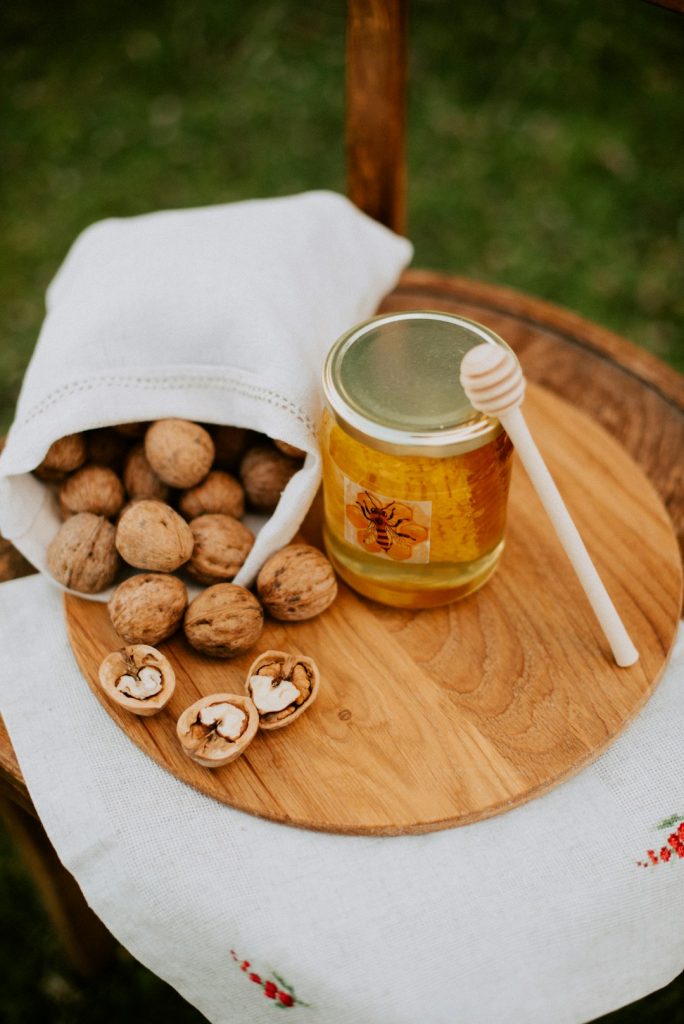 a-wooden-table-topped-with-a-jar-of-honey-and-nuts-pepjx1p8xq0